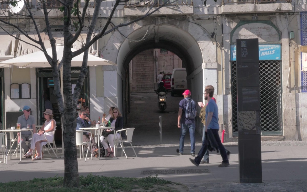 Outdoor cafe in the street and Uber Eats delivery man driving 