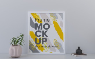 White Frame With Book And A Plant On The Shelf Mockup Template