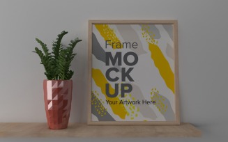 A Closeup Shot Of A Plant In A Vase Next To A Frame On A Gray Wall Mockup Template