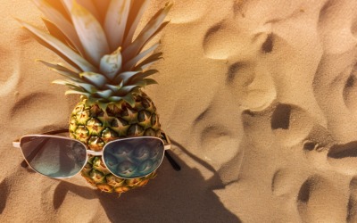 Halved pineapple and a sunglass kept on the sand 173