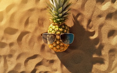 Halved pineapple and a sunglass kept on the sand 181