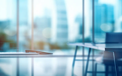 A blurry view of a modern office space with glass doors and windows, featuring natural light