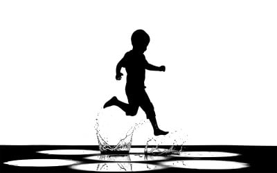 Niño a medio paso chapoteando en aguas poco profundas con vuelo aislado sobre fondo blanco