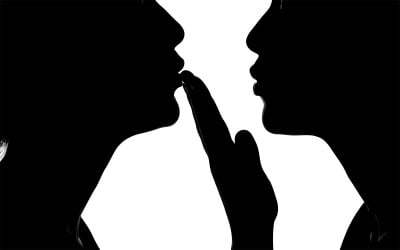 Silhouette of two faces in intimate conversation against neutral isolated on white background