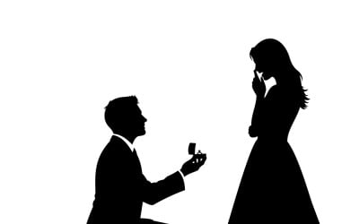 A man proposes to a woman with an engagement ring, kneeling in a silhouette design