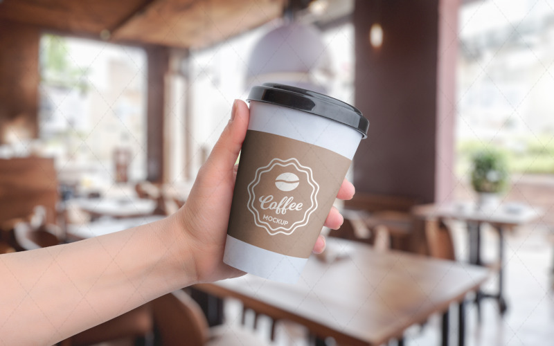 Mockup av pappersmugg, hållen i handen på ett kafé